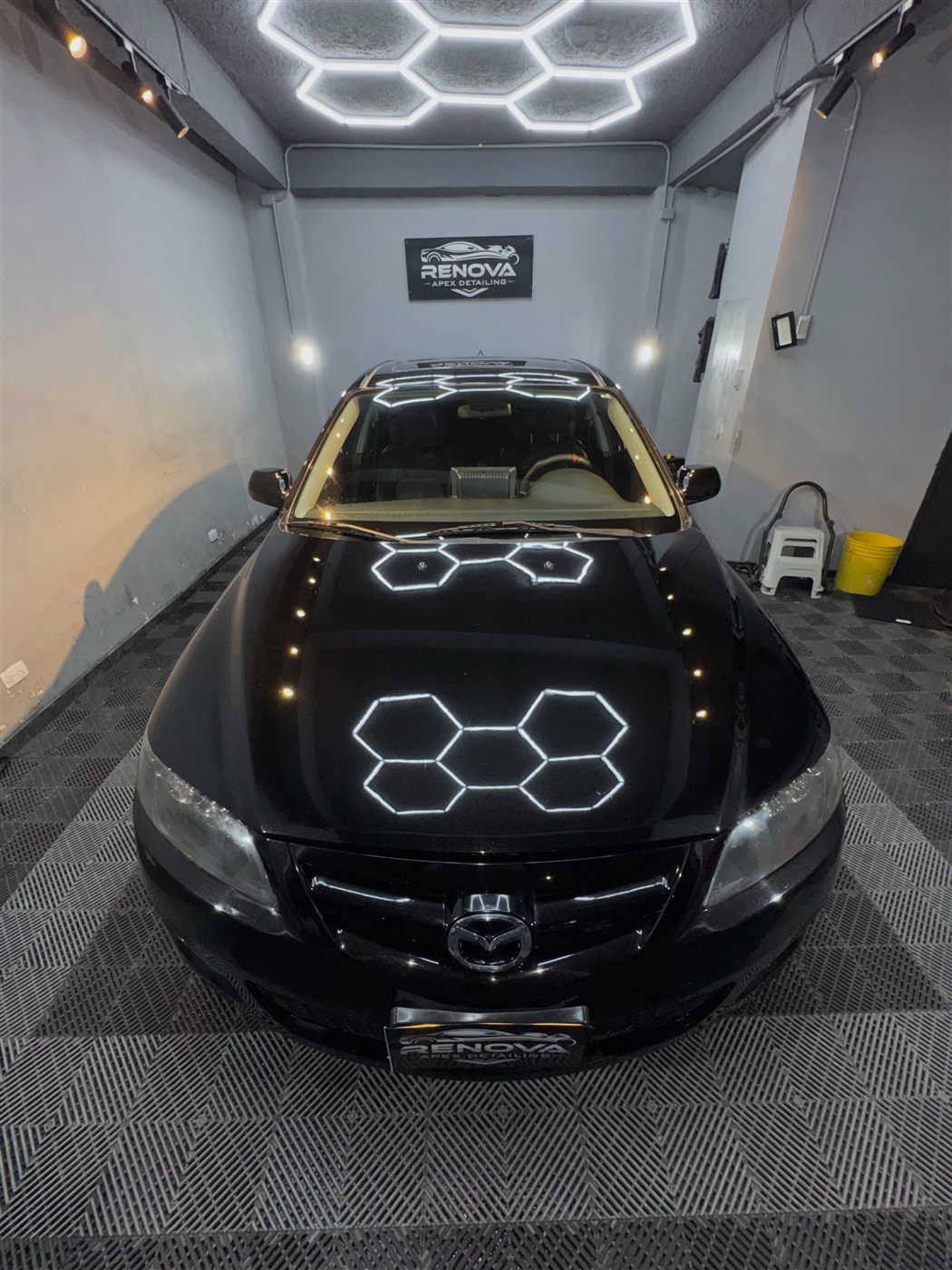 Capó de Mazda 6 negro reflejando las luces hexagonales tras la corrección de pintura, Bogotá
